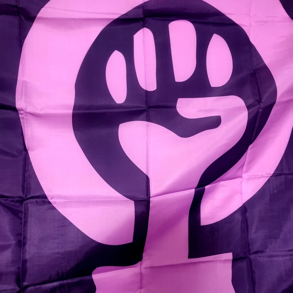 Détail du poing levé sur le drapeau féministe