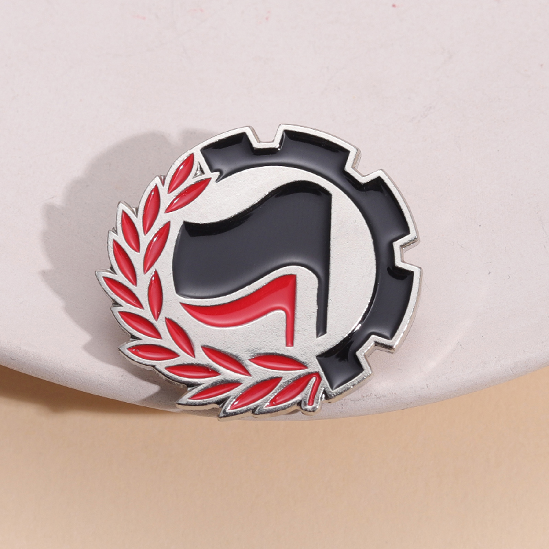 Pin antifasciste rouge et noir avec drapeaux, roue dentée et branche