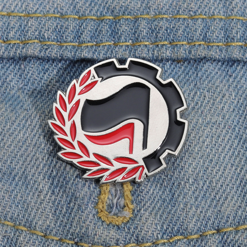 Pin antifasciste aux drapeaux noir et rouge porté sur une veste en denim