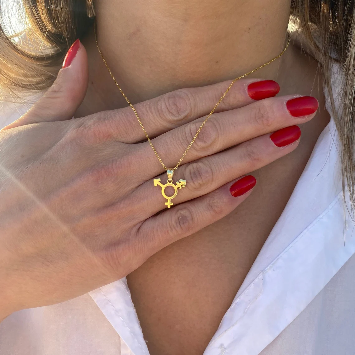 Collier symbole trans doré porté sur la peau